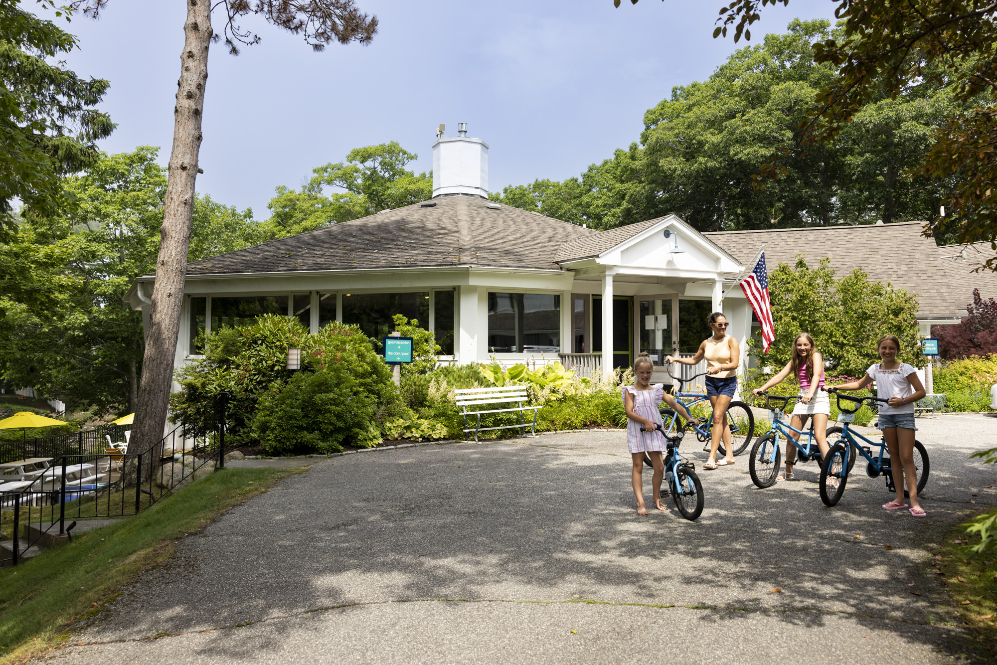 Children with bikes in front of a cottage surrounded by trees.