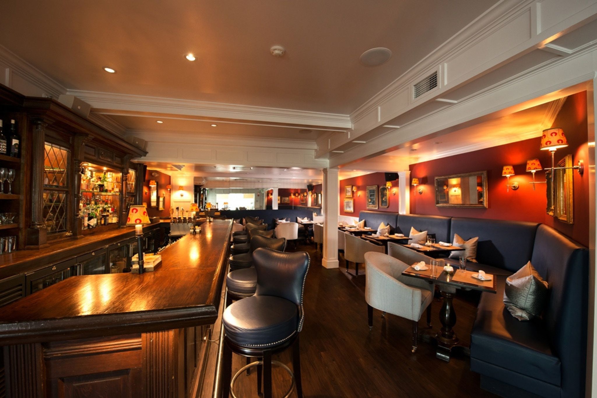 Cozy restaurant interior with a wooden bar, tables, and dim lighting.