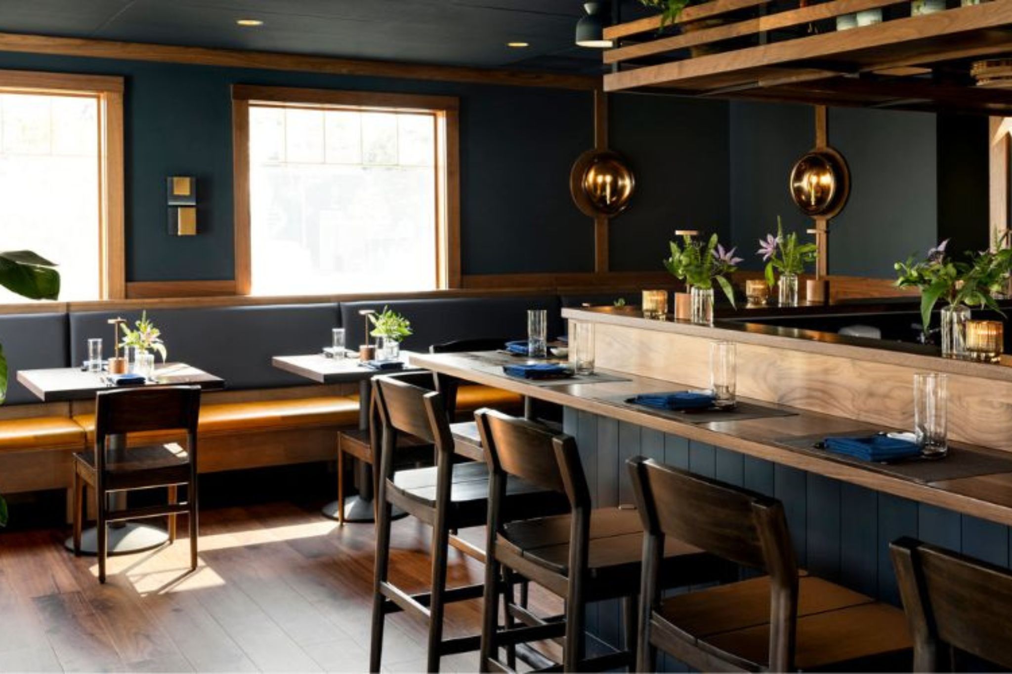 Cozy restaurant with wooden tables, chairs, and green plants.