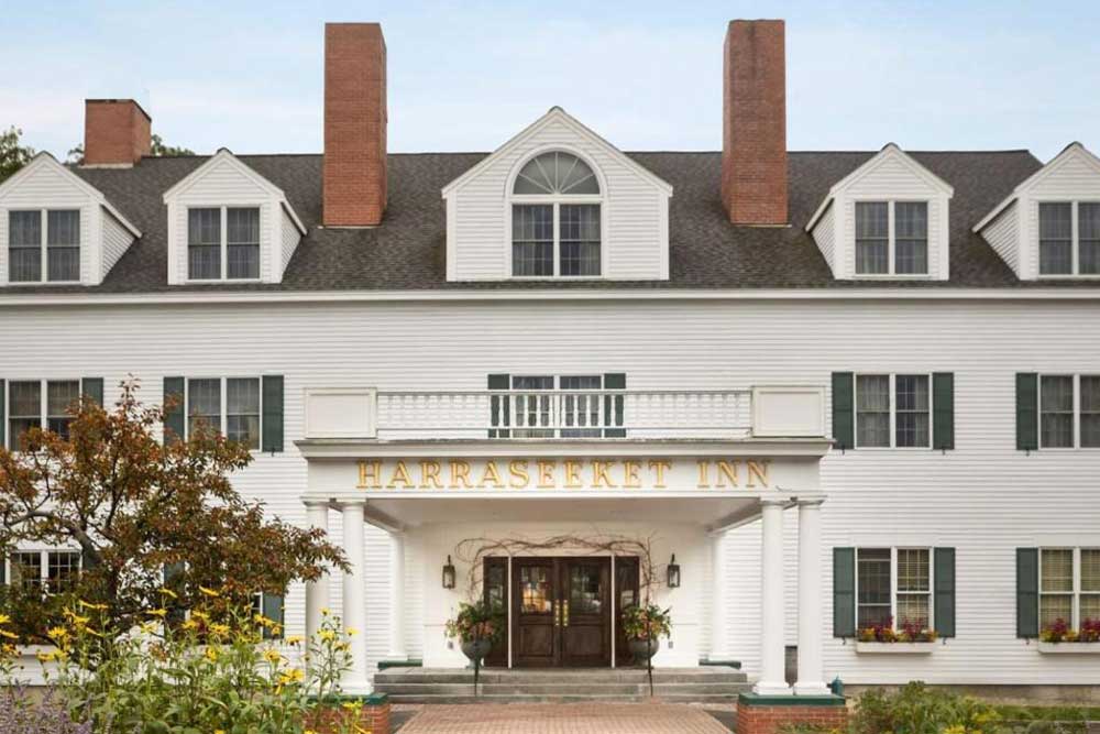 White colonial-style inn with brick chimneys and flower boxes.