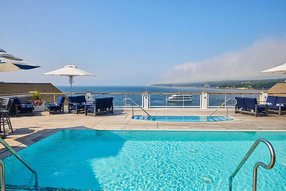 Rooftop pool with ocean view, lounge chairs, and umbrellas.