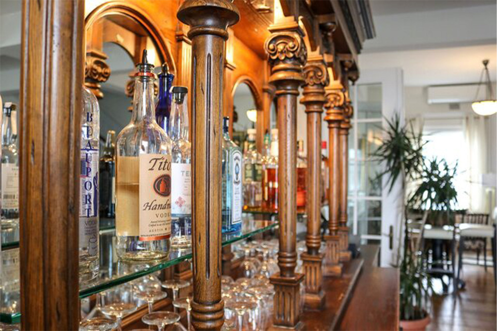 Elegant wooden bar with liquor bottles and glassware, set in a bright, modern room.
