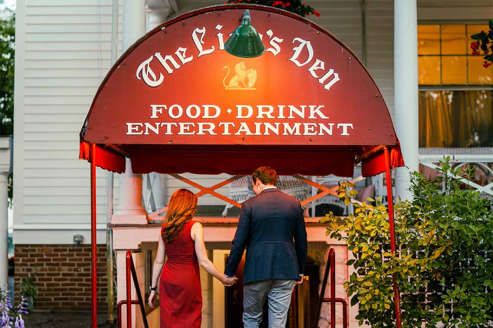 Couple entering red awning labeled "The Lion's Den."