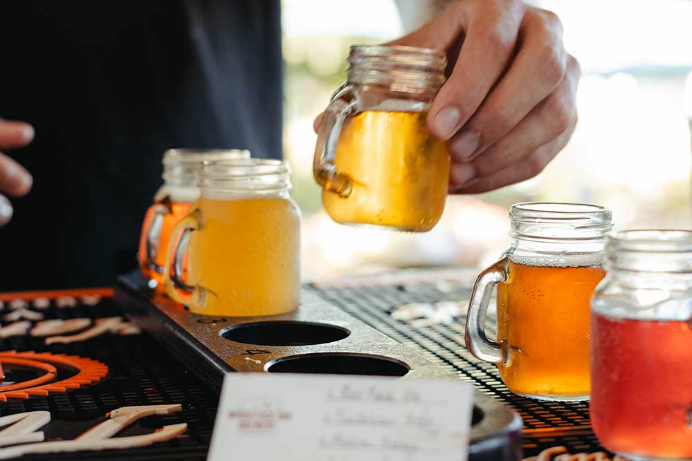 Sampler tray of craft beers in glass jars on a bar counter.
