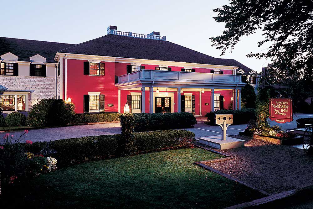 Hotel exterior with red facade, porch, and evening lighting.