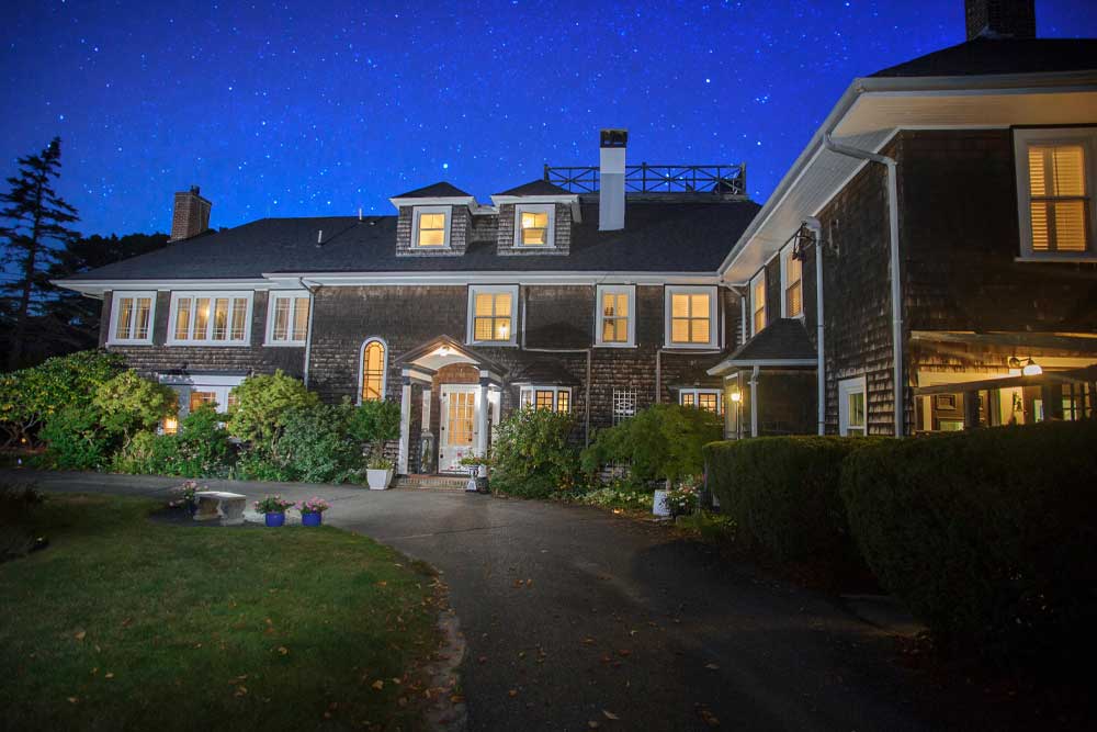 A large house at night, warmly lit under a starry sky.