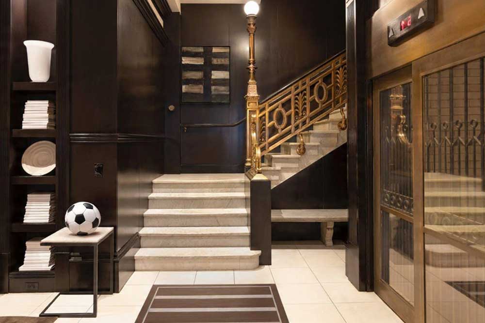 Elegant hotel lobby with stairs, elevator, and decorative items.