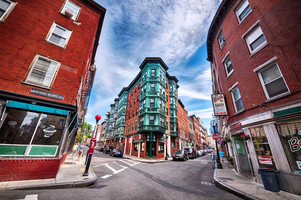 Narrow street intersection with colorful brick buildings under a vibrant blue sky.