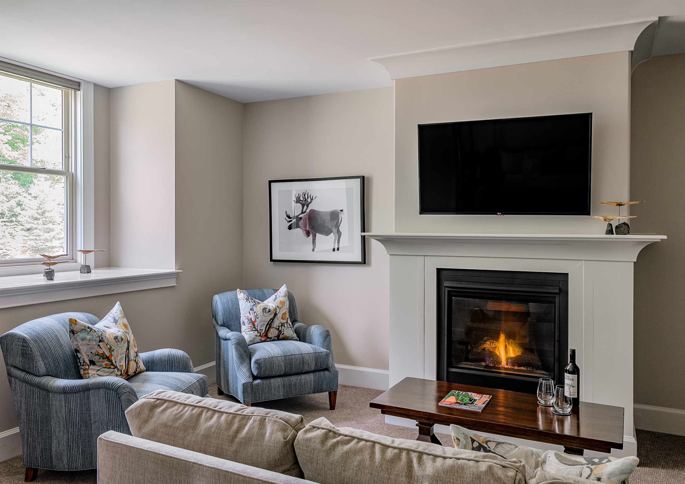 Cozy living room with blue chairs, a fireplace, and wall-mounted TV.