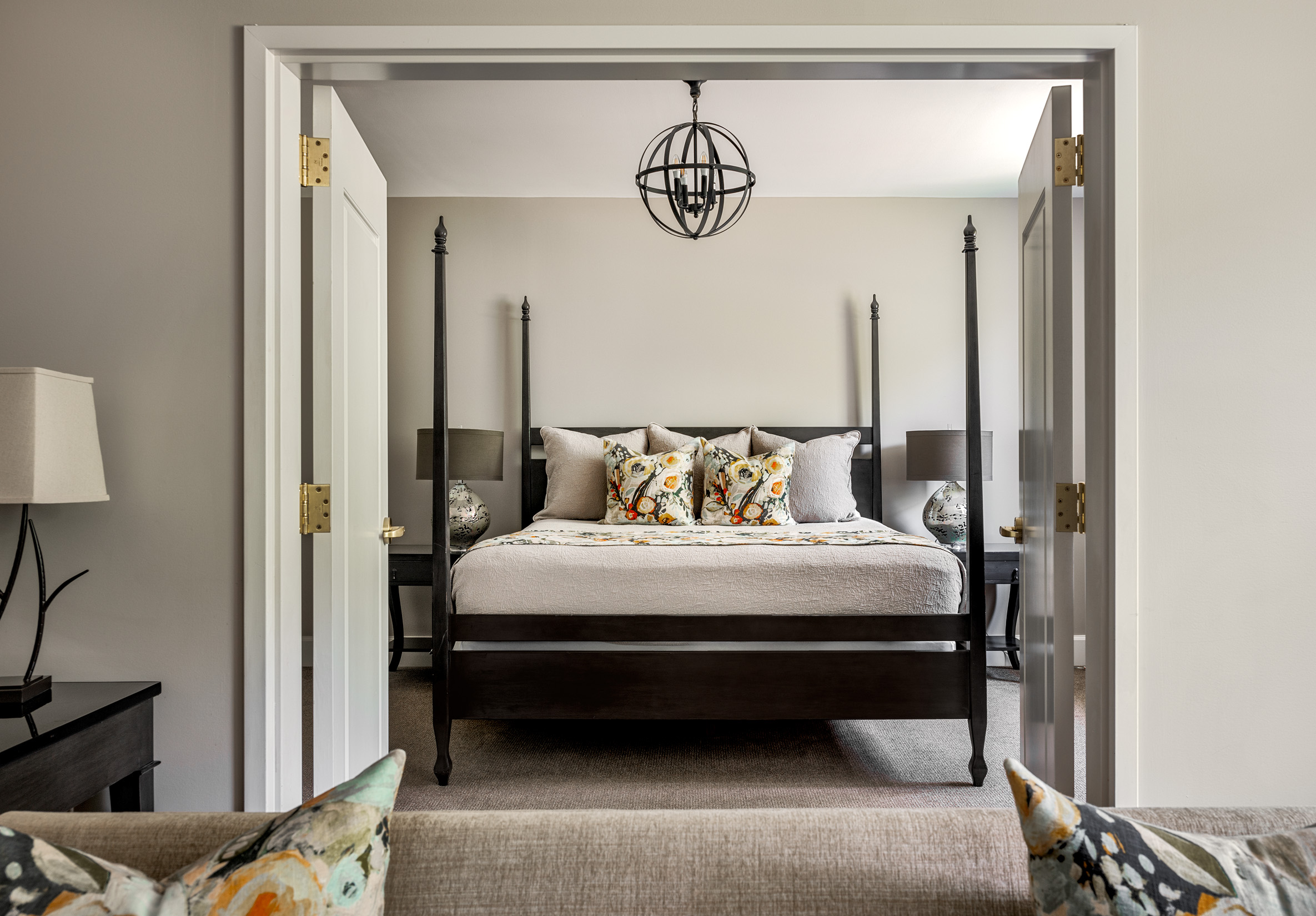 Four-poster bed in a cozy bedroom with decorative pillows and a hanging light fixture.