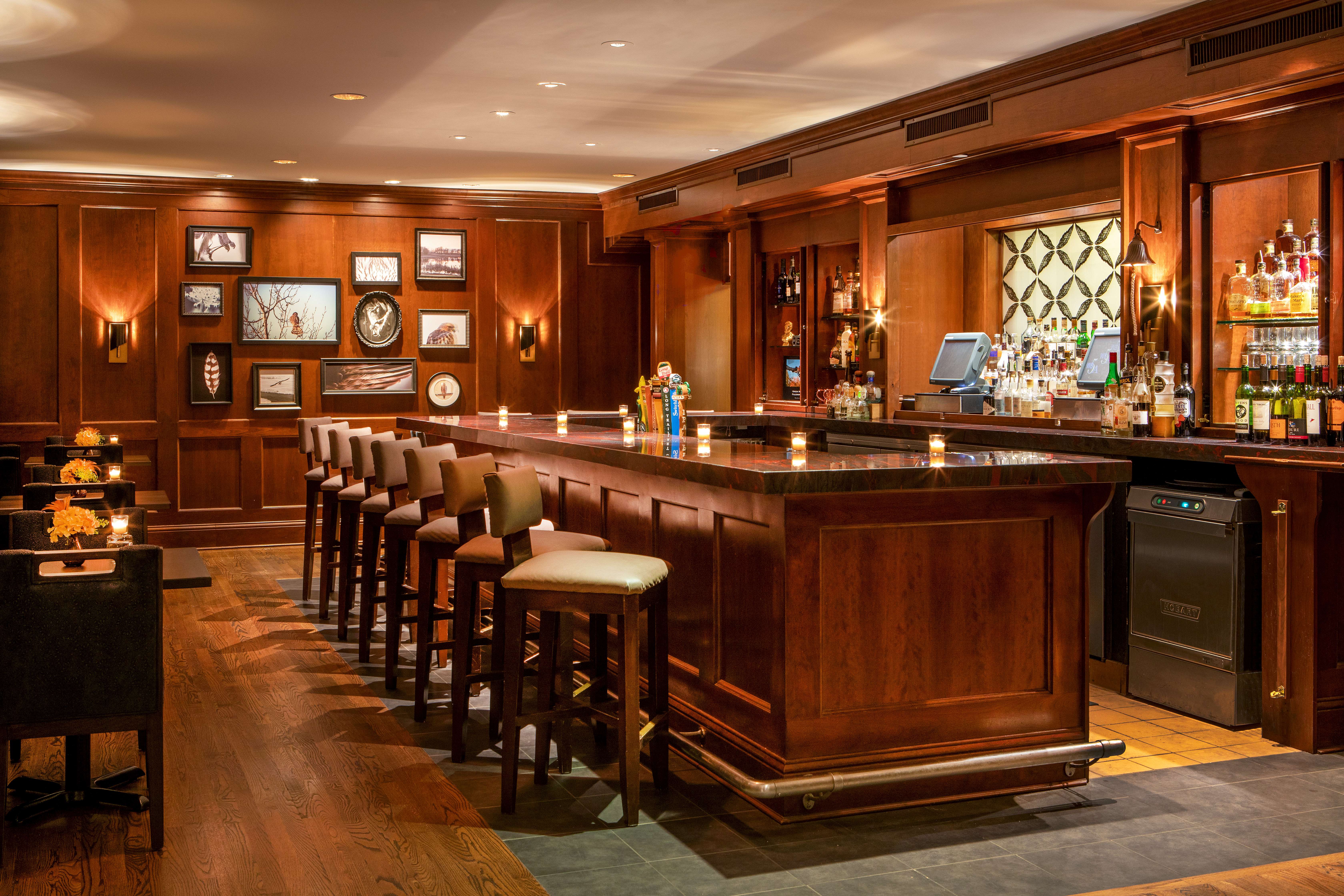 Warmly lit traditional pub bar with wooden stools and paneled counter