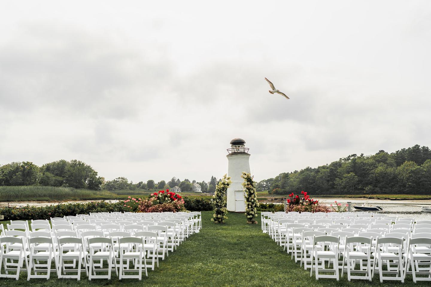 Chairs arranged for a ceremony, positioned in front of The Nonantum Resort’s iconic lighthouse.