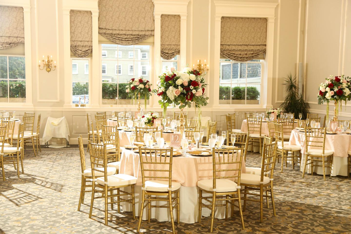 Elegant banquet hall with floral centerpieces and gold chairs.