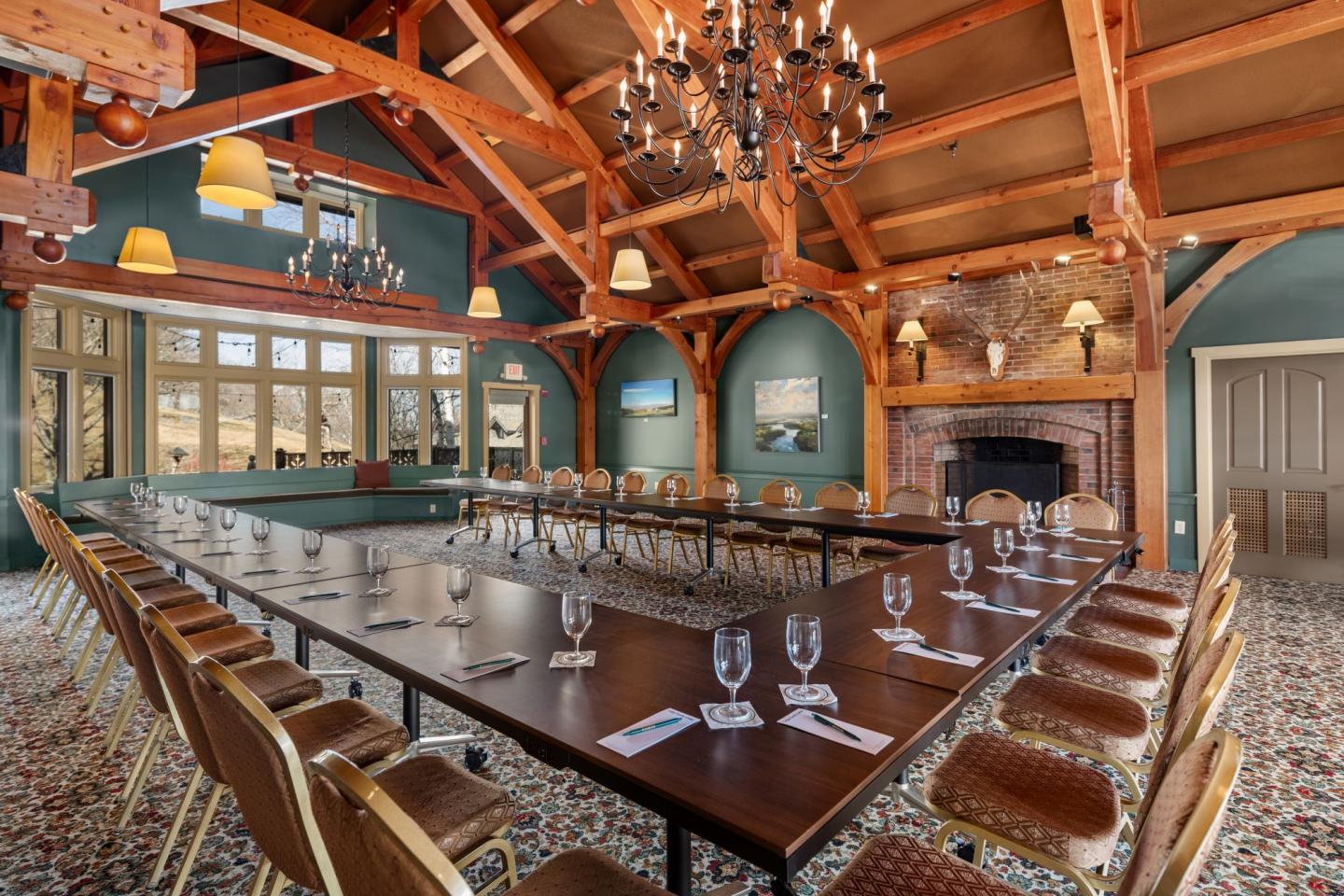 Elegant conference room with wooden beams, chandelier, and arranged chairs around a large table.