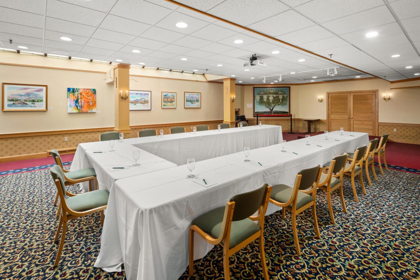 Conference room with a U-shaped table setup, white cloth, and wooden chairs.