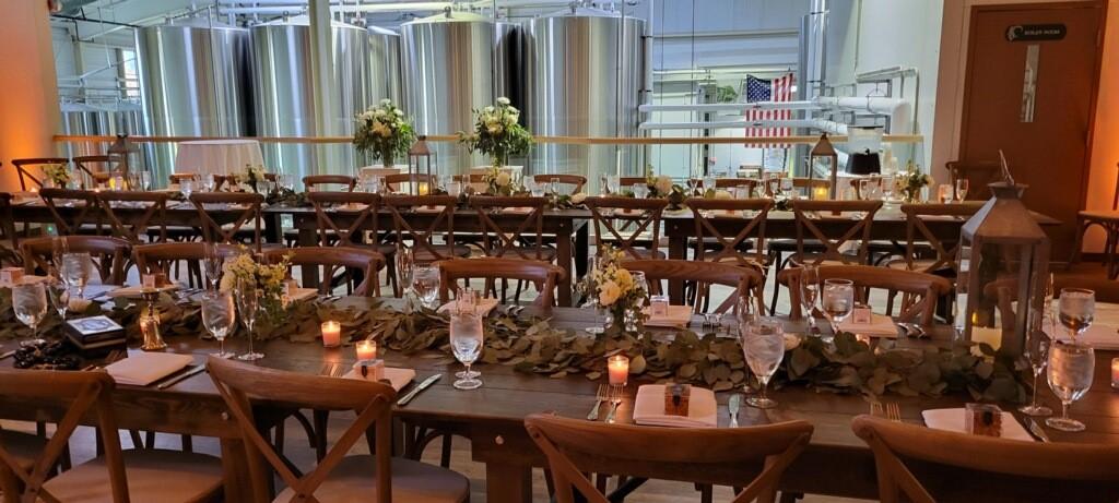 Elegant banquet table setup with candles and flowers in an industrial setting.