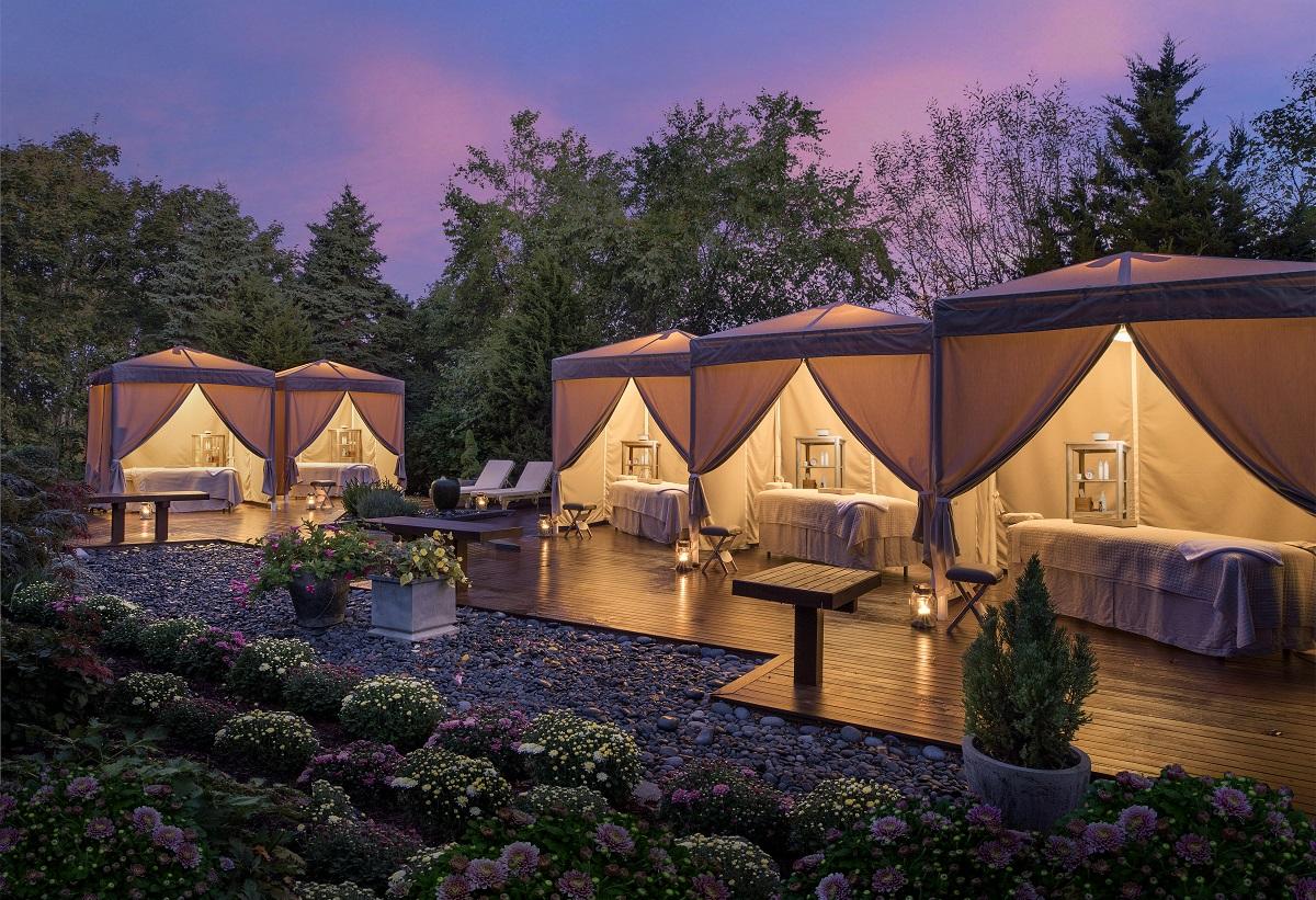 Elegant outdoor cabanas lit at dusk with lush greenery and flowers.