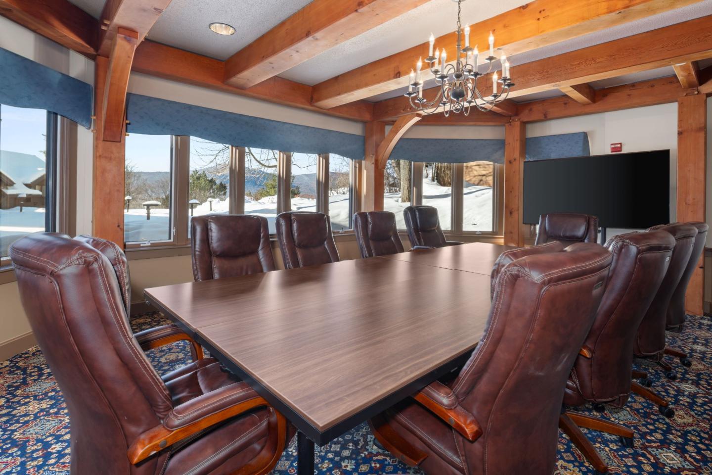 Spacious conference room with leather chairs, wooden beams, and large windows.