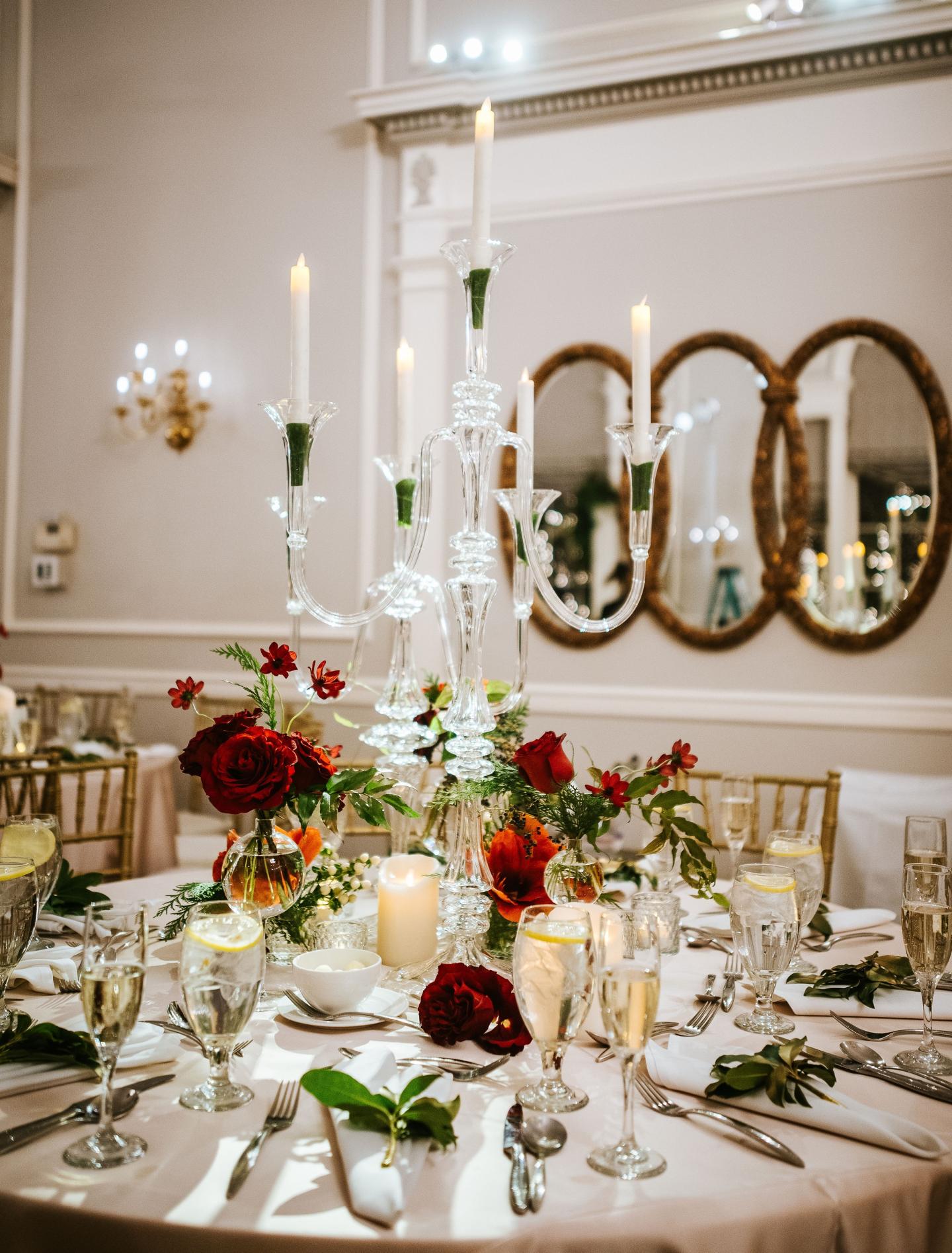Elegantly set table with flowers, candles, and glassware in a formal dining room.
