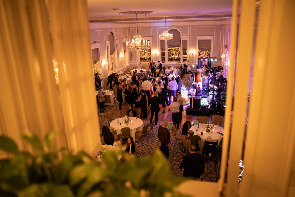 Elegant ballroom with guests, round tables, and purple lighting.