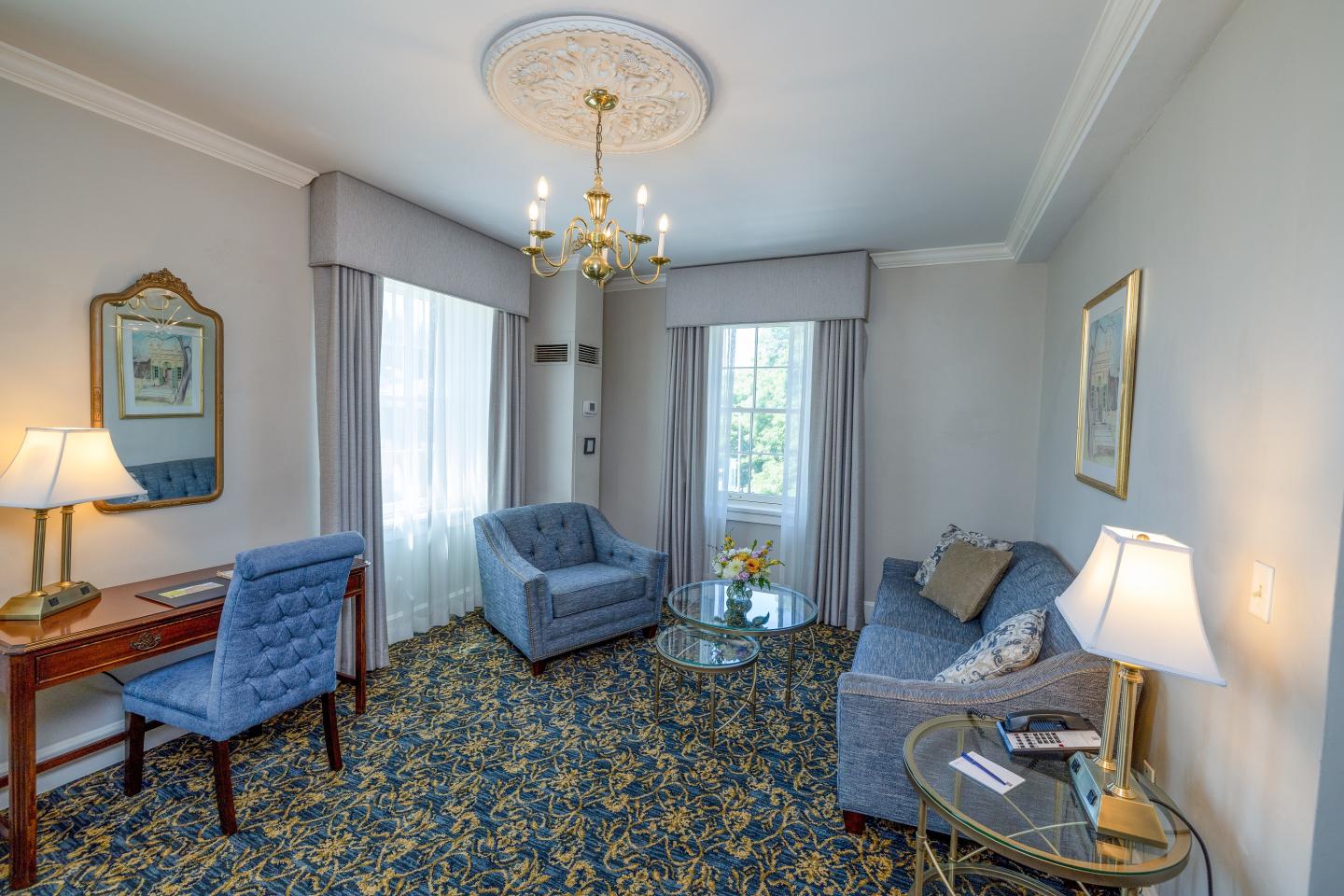Elegant living room with blue chairs, sofa, table, and chandelier.