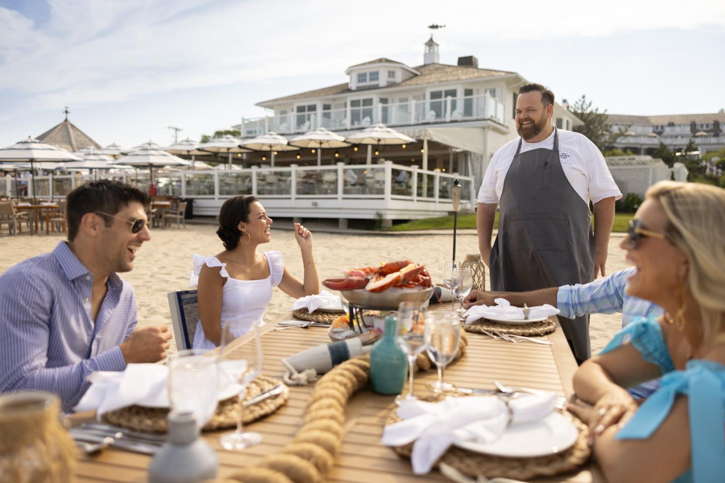 Outdoor clambake with people at a beachside restaurant table.