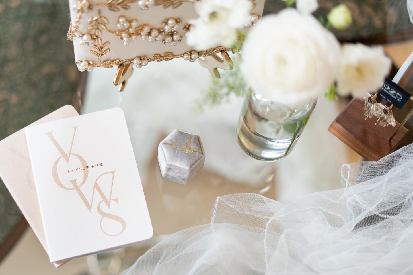 Wedding-themed items on a table, featuring a vows booklet and white flowers.