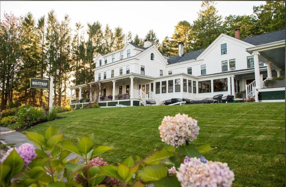 Victorian-style white building with green lawn and blooming hydrangeas.
