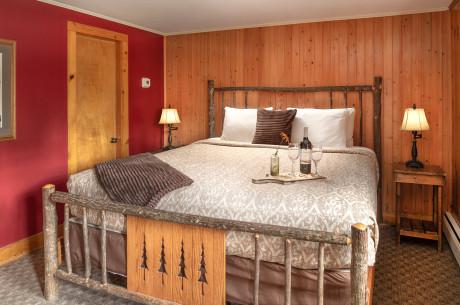 Cozy bedroom with a wooden bed, wine tray, and soft lighting.