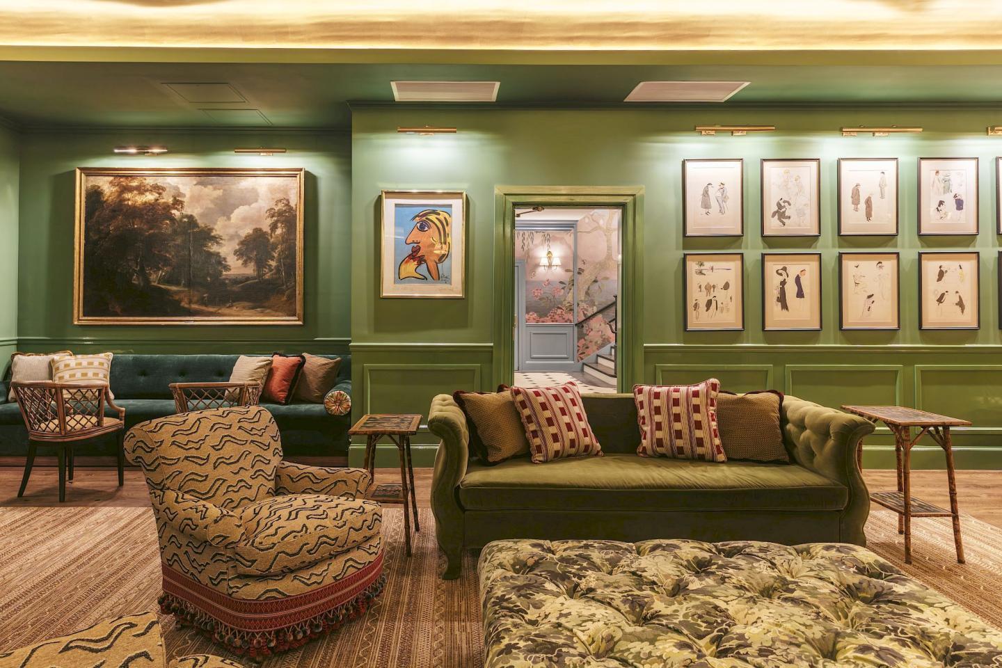 Elegant lounge with green walls, colorful sofas, and framed artwork.