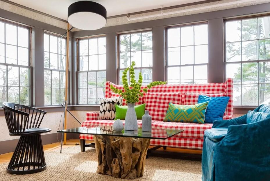 Bright living room with a red checkered sofa, colorful pillows, and a glass coffee table.