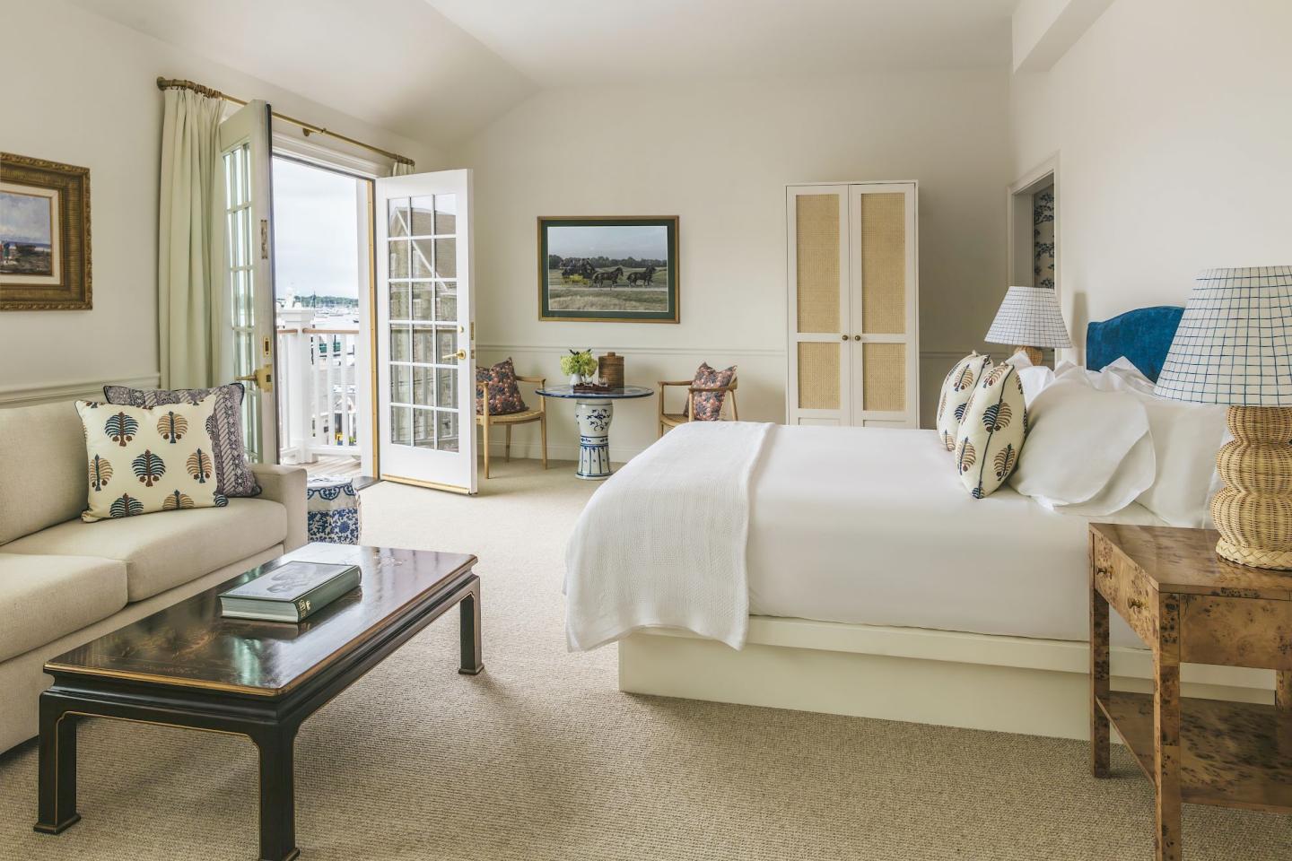 Spacious hotel room with a bed, sofa, and open balcony doors. Bright and elegant decor.