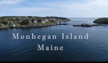 Aerial view of Monhegan Island, Maine, with blue sky and calm water.