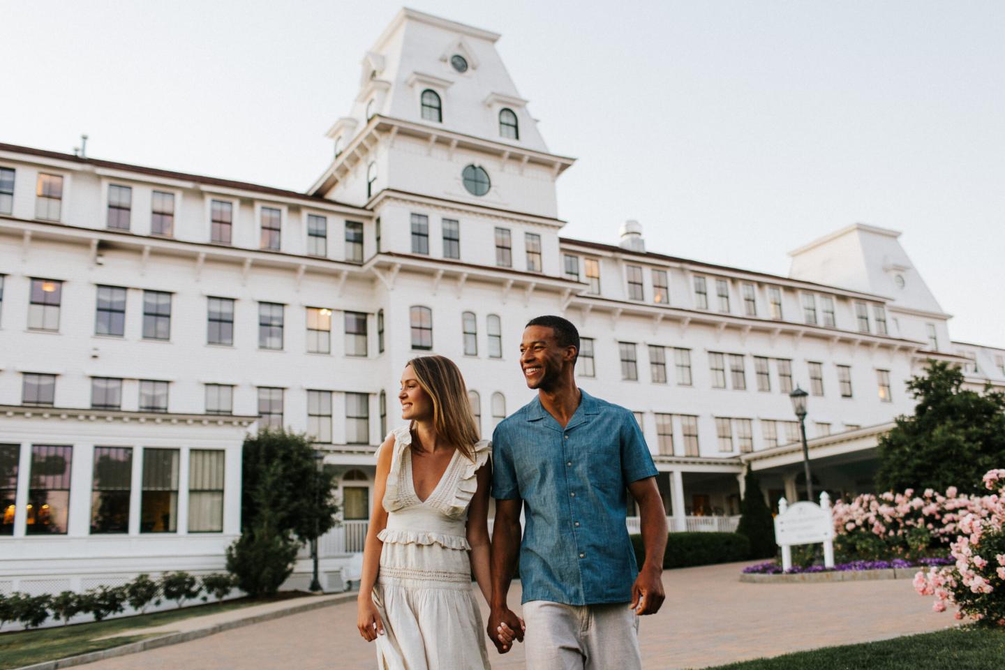 Couple walking happily in front of a large white building.
