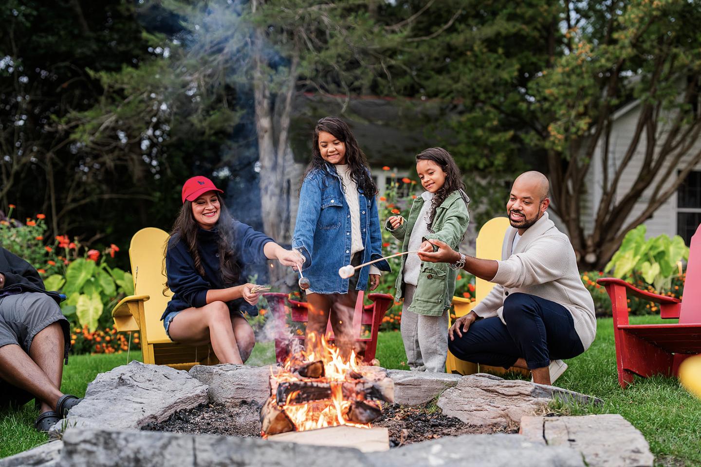 Family roasting marshmallows around a backyard firepit.