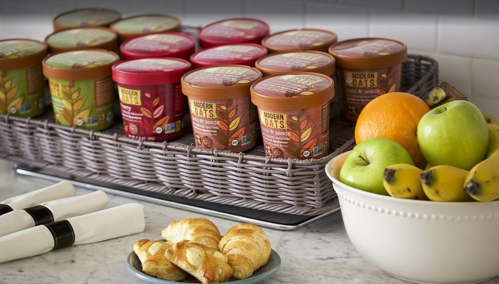 Ice cream tubs in a basket, bowl of fruit, and plate of croissants on a counter.BReakfas