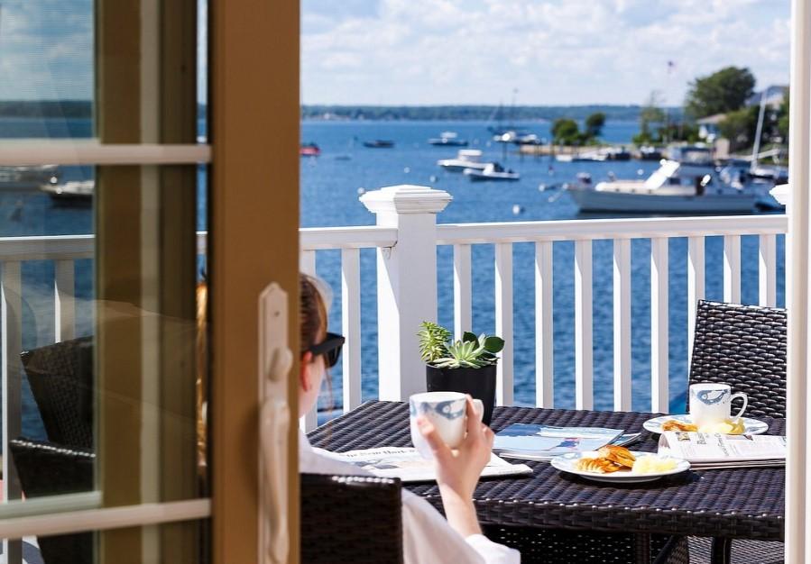 Person relaxing with coffee on a balcony overlooking a lake.