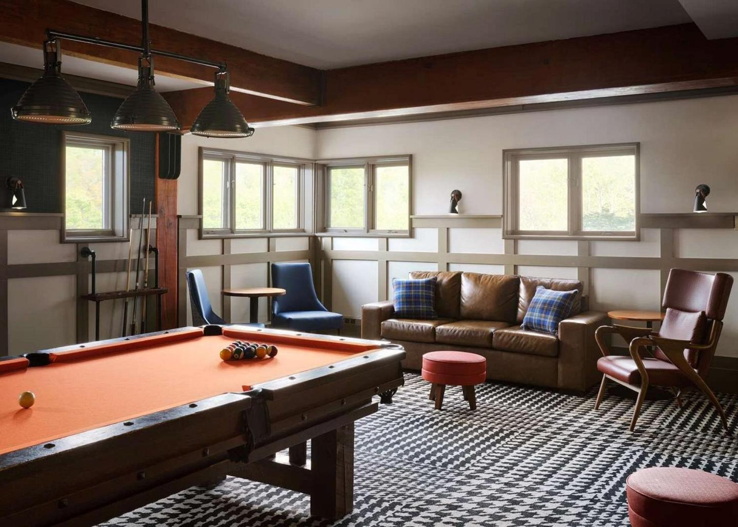 Cozy game room with a pool table, sofa, and large windows.