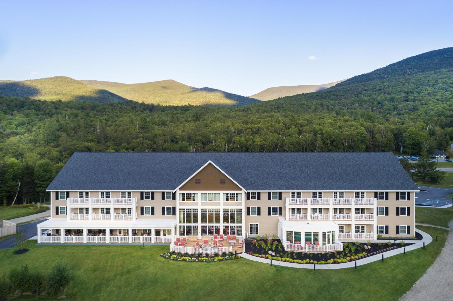 Large beige building with white balconies, set against a mountain backdrop.