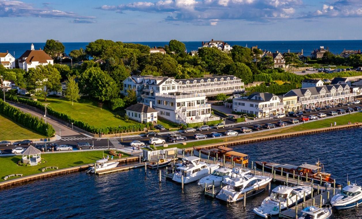 Coastal town with marina, boats, and houses under a blue sky..2025