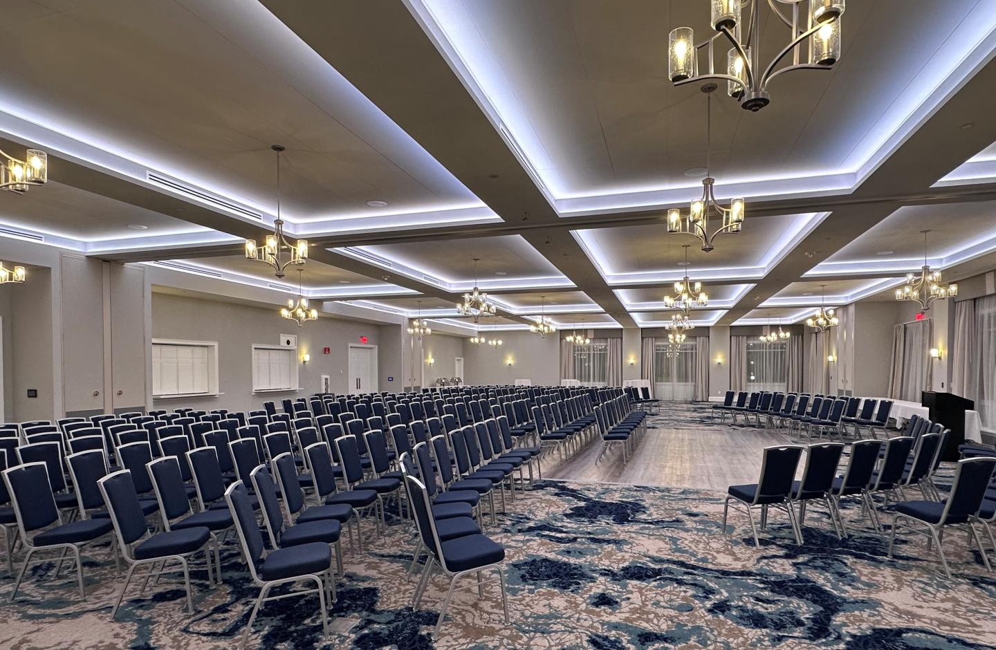 Spacious conference room with rows of blue chairs and modern lighting.