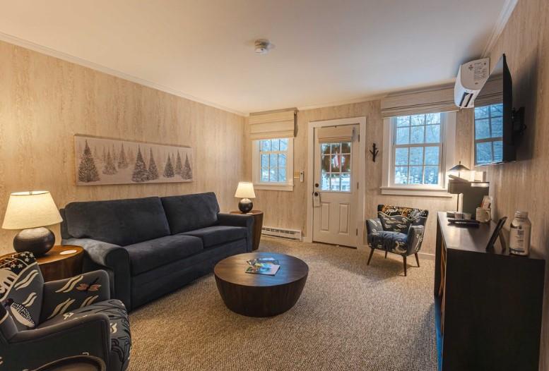 Cozy living room with sofa, armchair, coffee table, and lamp-lit decor.