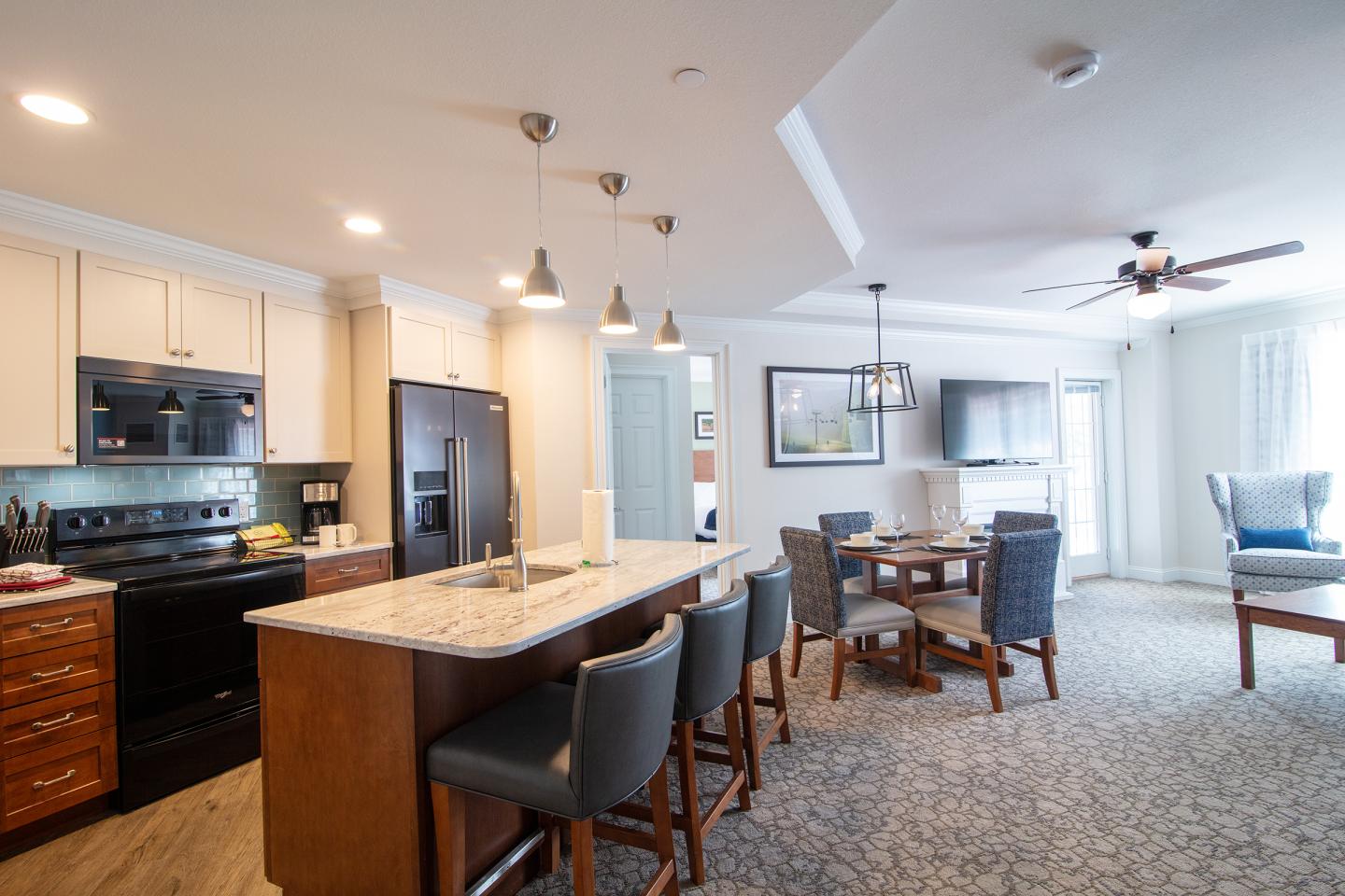 Modern kitchen and living area with island, dining table, and ceiling fan.