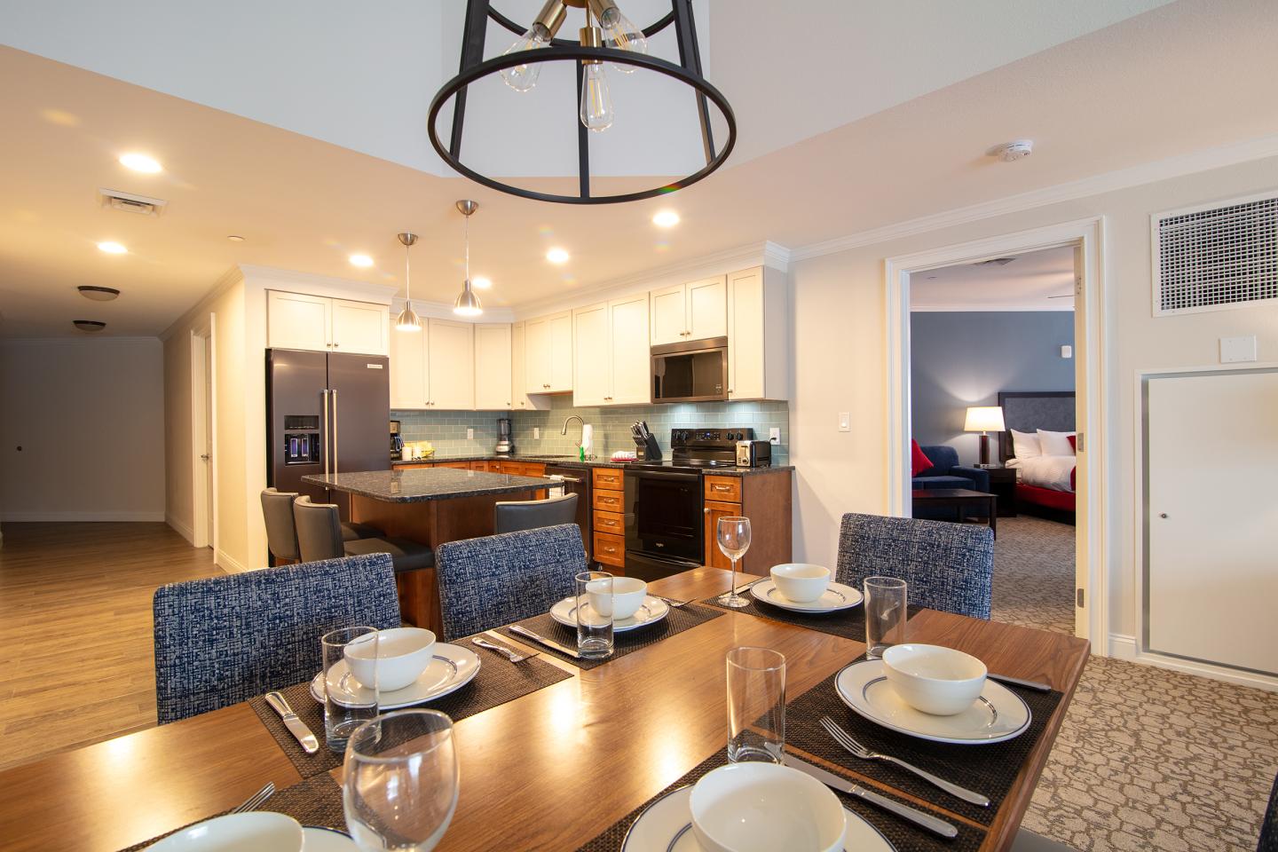 Dining area with set table, modern kitchen, and adjoining bedroom.