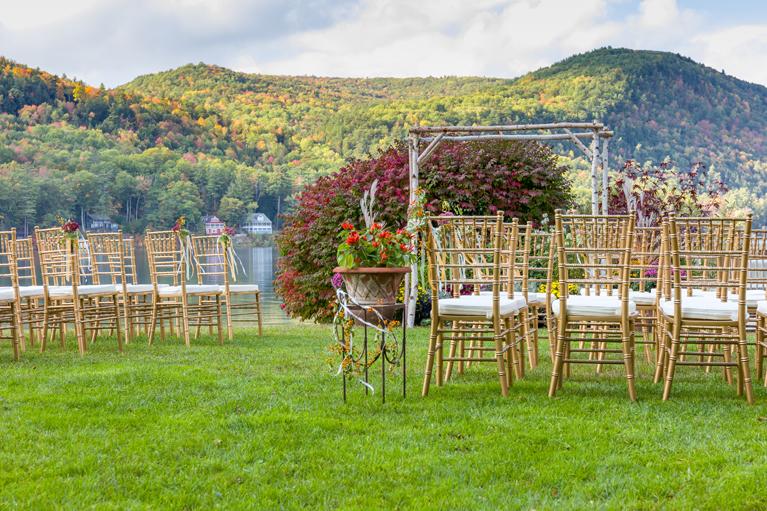 Outdoor wedding setup with chairs, flowers, and mountain view.