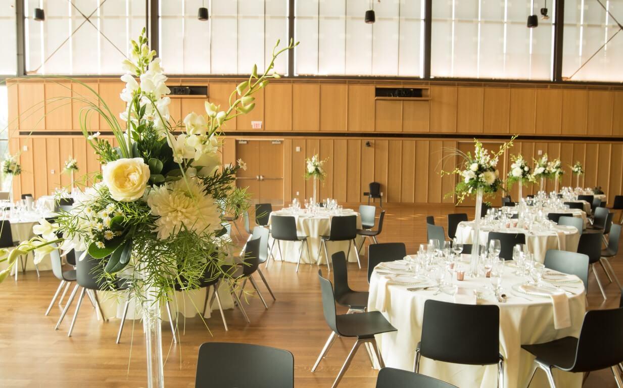 Elegant banquet hall with floral centerpieces and round tables.