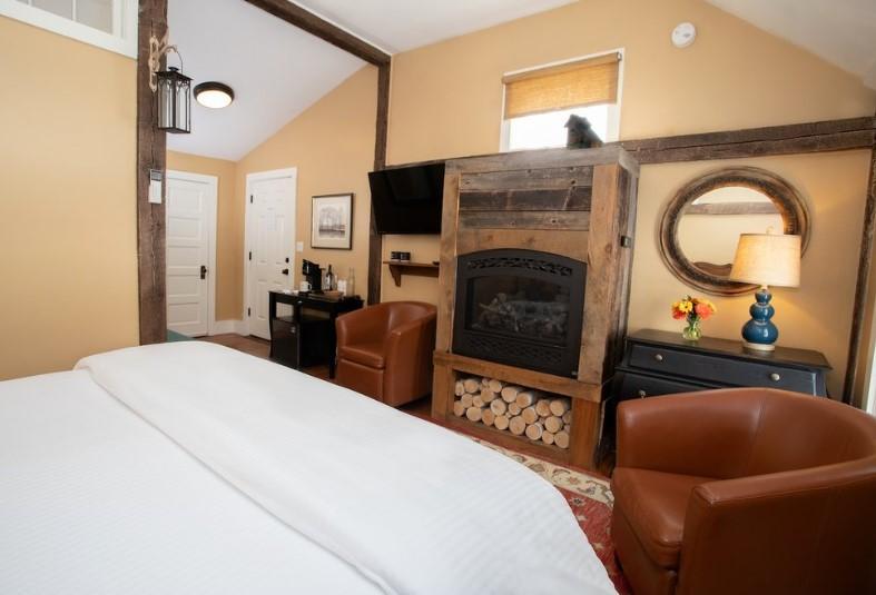 Cozy bedroom with armchairs, fireplace, and decorative mirror.