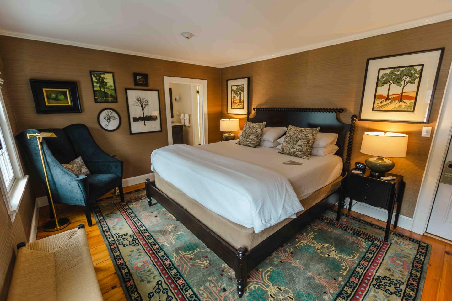 Cozy bedroom with a large bed, art on walls, and warm lighting.