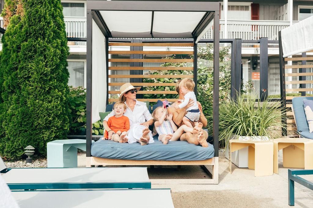 Family relaxing on a patio daybed, surrounded by greenery.