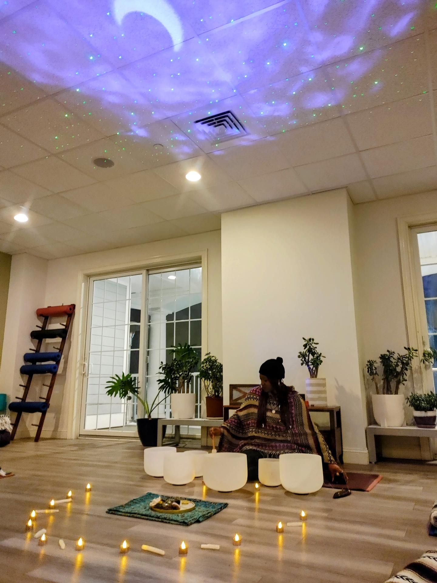 Calm room with candles and plants, moonlight projection on ceiling.